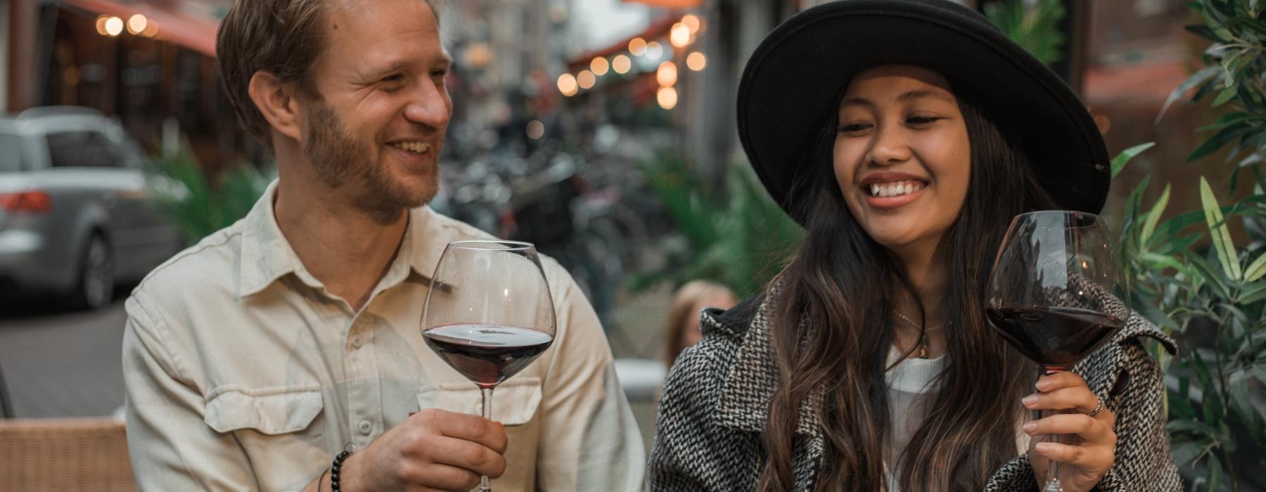 a man and a woman holding wine glasses and smiling